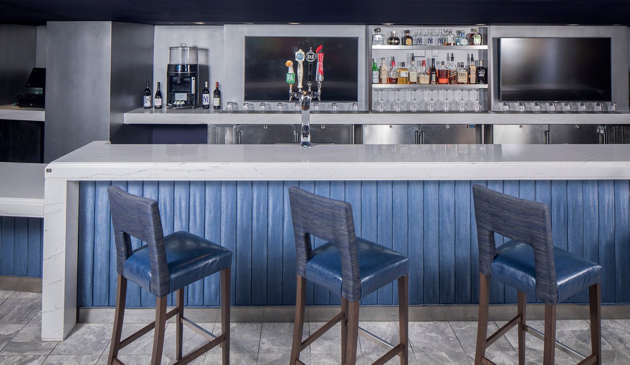 A bar in the Legned's Suite in Yankee's Stadium featuring a spinoff of Yankees’ pinstripe blue plays with white quartz countertops.