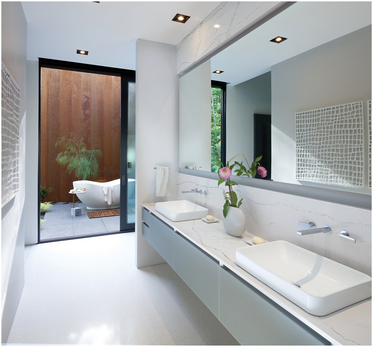 A modern bathroom with a floating vanity, white quartz countertops and backsplash, large mirror, white flooring, and wooden accents near the stand-alone tub.