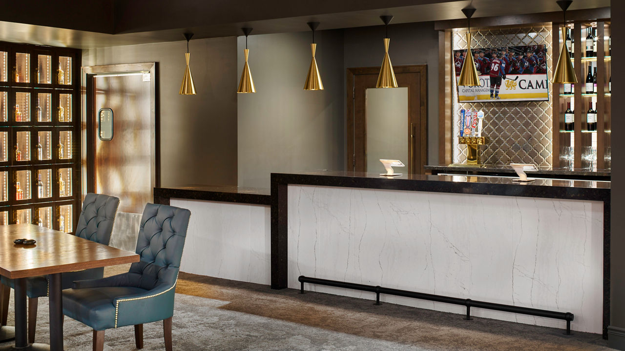 Gold pendant lights highlight a bar made from black and white quartz in Pepsi Center's Club Lexus.