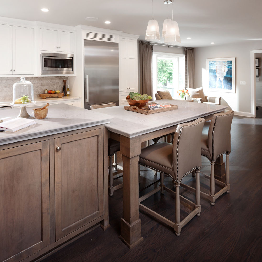 A kitchen with white upper cabinetry and brown lower cabinets and seating around a kitchen table.