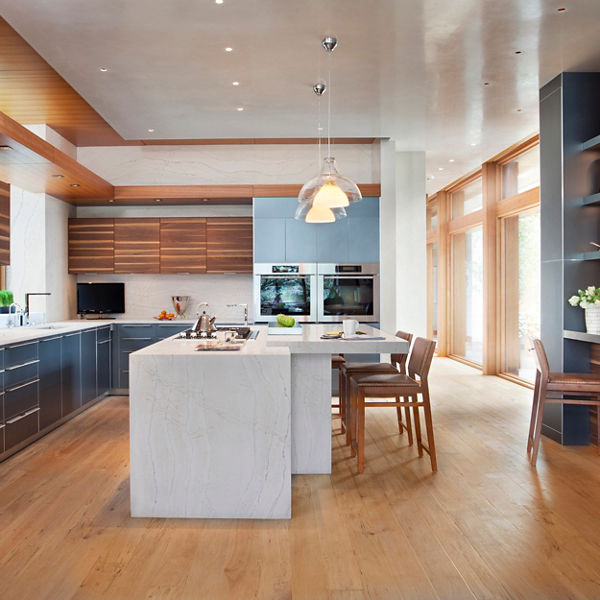 a modern kitchen with sleek black cabinets, wooden upper cabinets, a center double waterfall-edge island topped with white quartz countertops with two pendant lights overhead