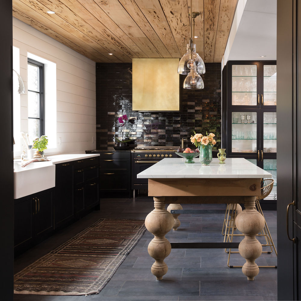 a gorgeous kitchen with black cabinets, white quartz countertops, black and gold quartz backsplash, black flooring, and wooden ceilings.