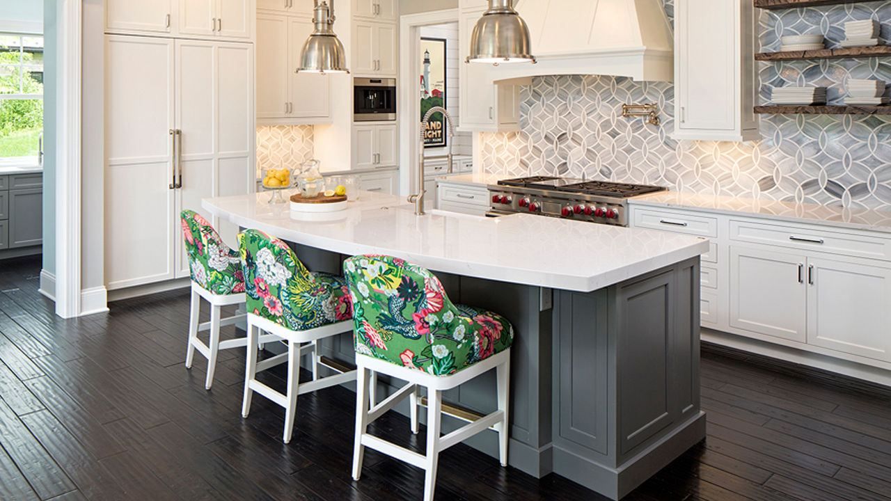 Upholstered kitchen island stools featuring a floral print surrounding a dark brown kitchen island topped with Cambria Ella quartz countertops.