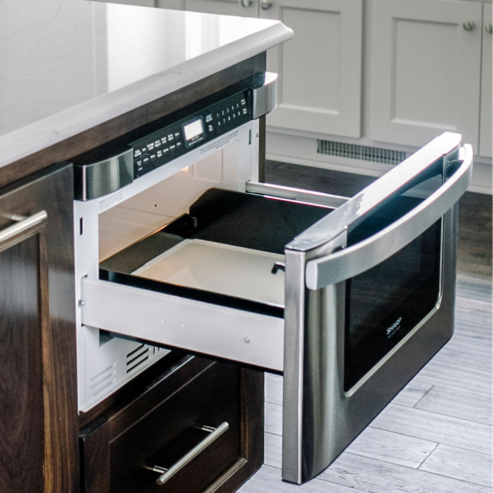 A kitchen island with a Cambria Ella quartz countertop and a built-in microwave drawer.