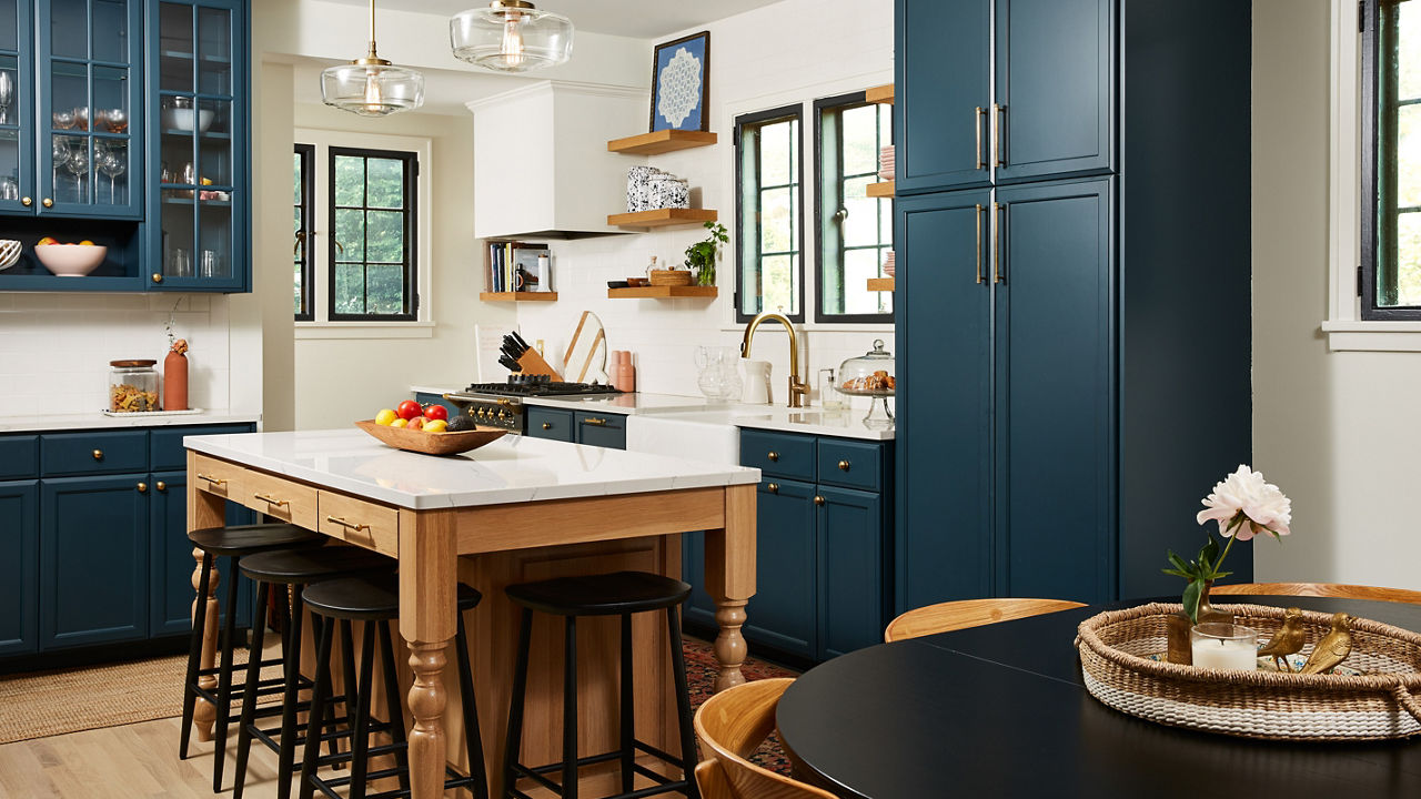 A gorgeous kitchen with cobalt blue cabinets, wooden open shelving and isalnd topped with white quartz countertops.