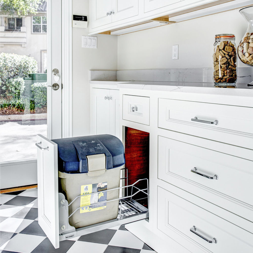 a laundry room with white cabinets and white quartz countertops and a pet food storage bin for easy access