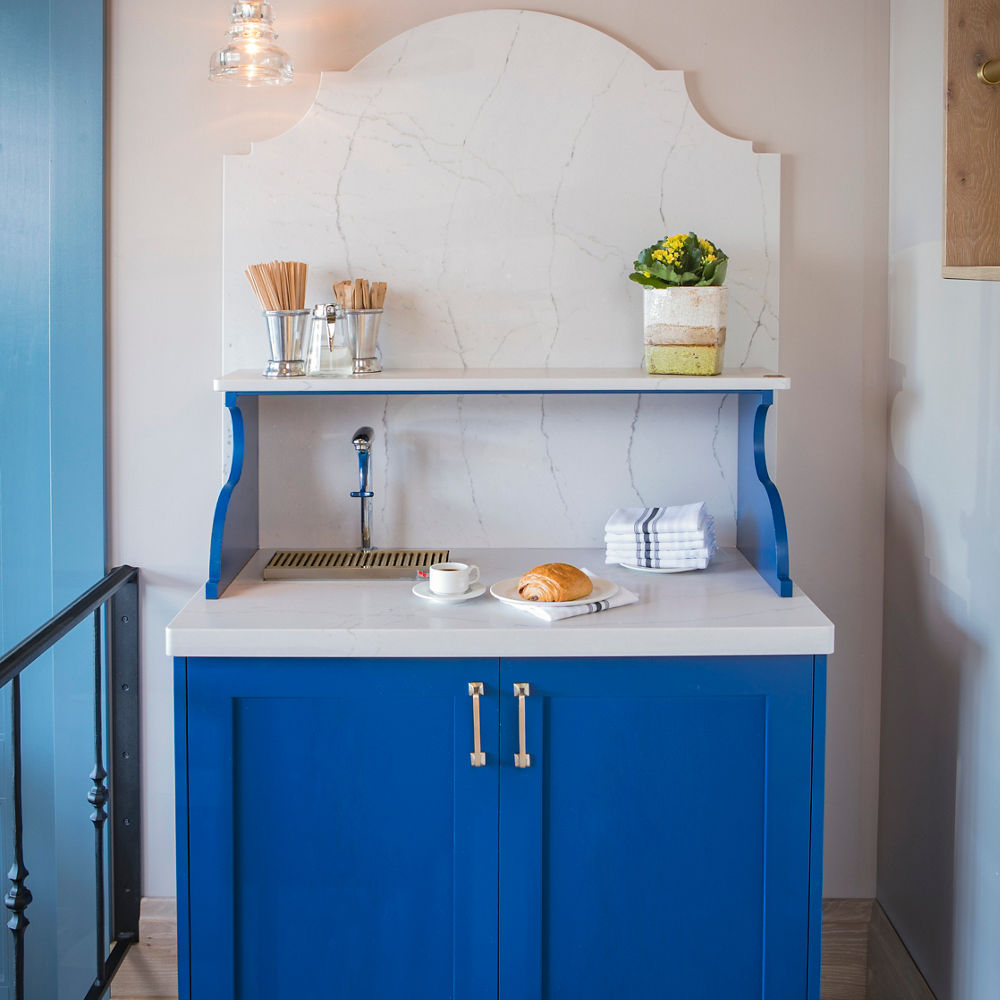 A blue beverage station with a Cambria Ella Matte quartz countertop and siding.