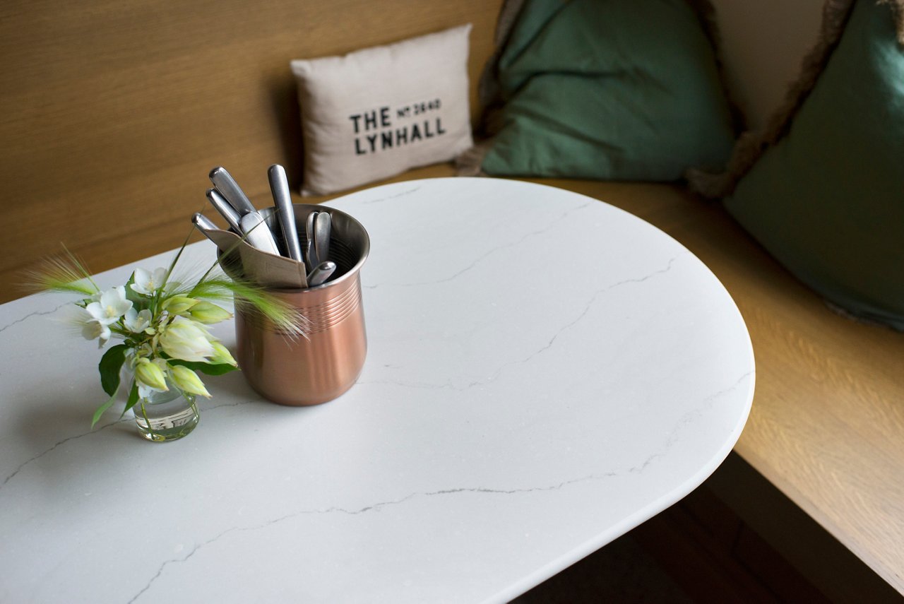 A table around a bench at The Lynhall featuring a Cambria Ella Matte quartz countertop.