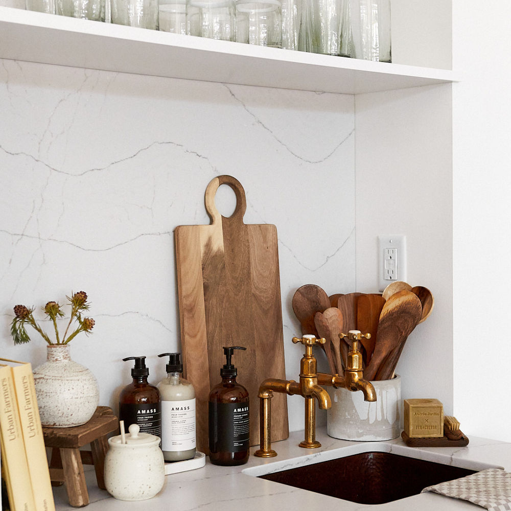 a kitchen in a retail store with white quartz countertops and matching backsplash, with various health and beauty products.