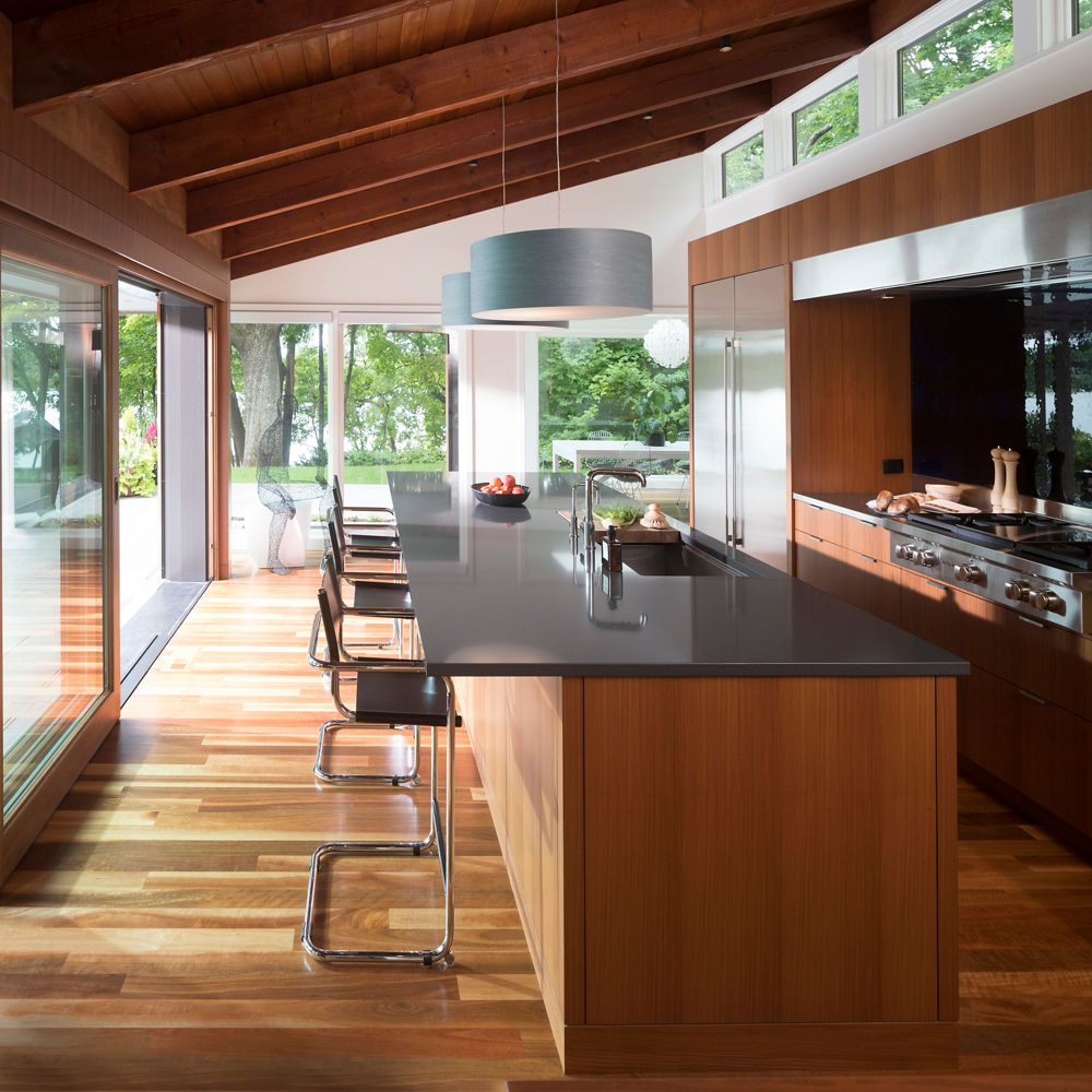 A kitchen with wooden floors and siding with a counter and kitchen island featuring Cambria Fieldstone quartz countertops.