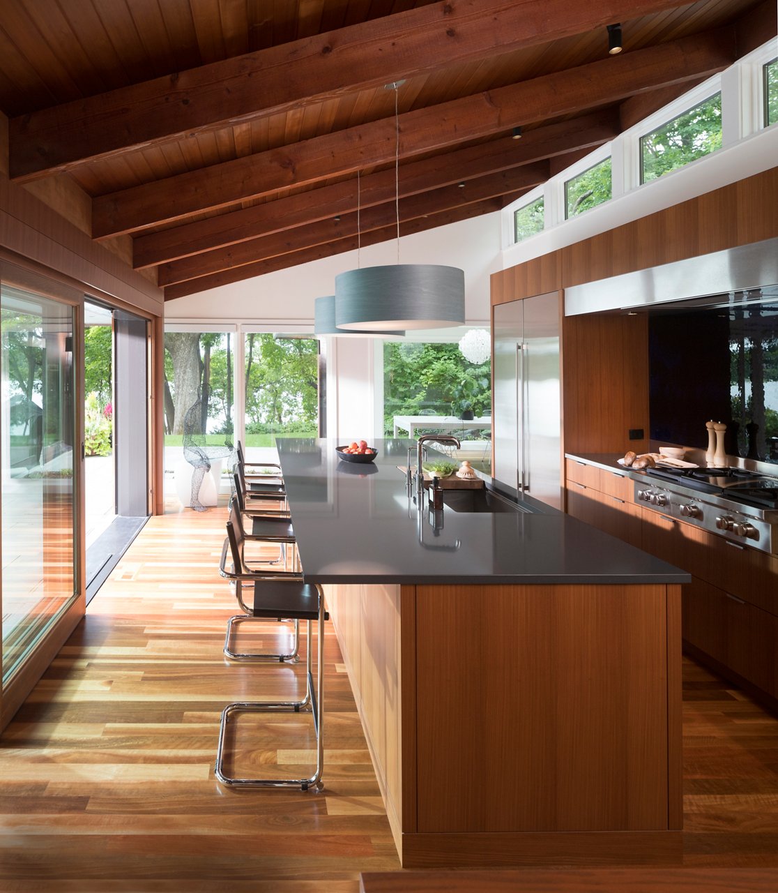 A kitchen with wooden floors and siding with a counter and kitchen island featuring Cambria Fieldstone quartz countertops.