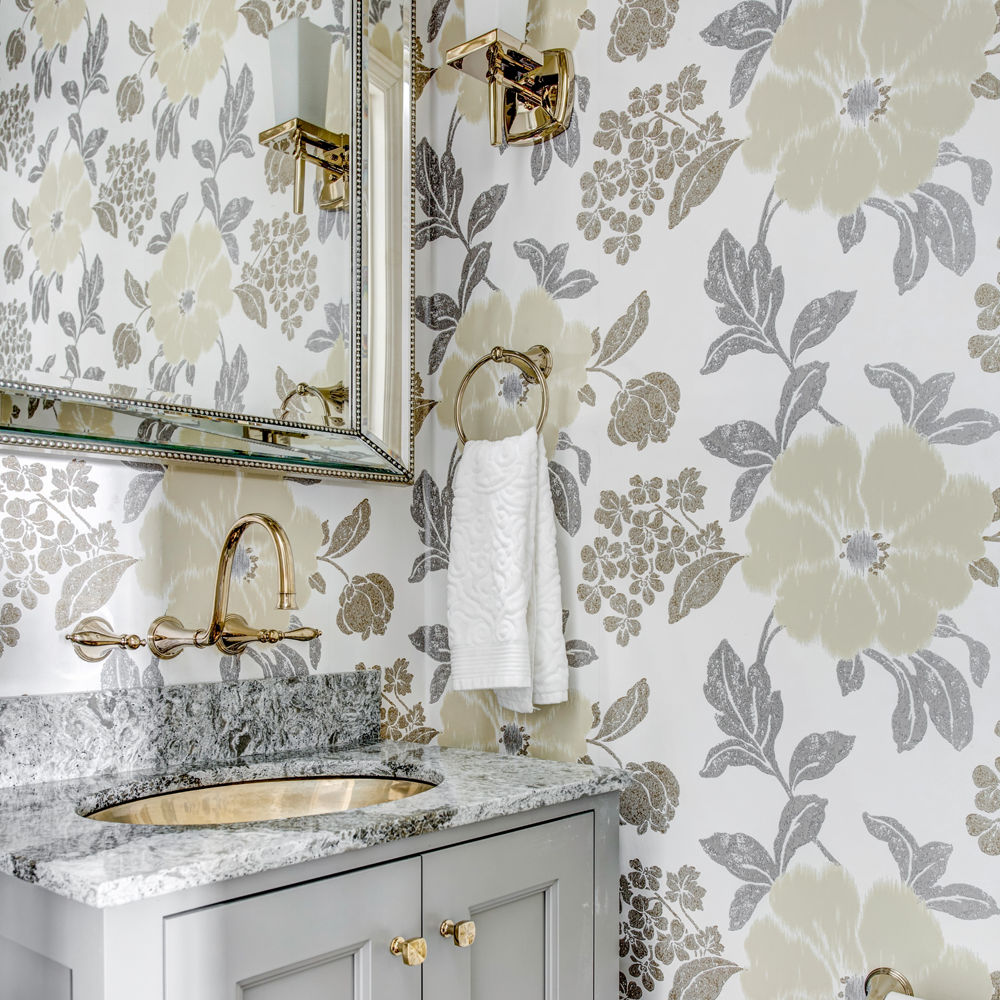 a powder bathroom with a small vanity topped with quartz countertops, bold patterned floral wallpaper, and gold accents in the hardware, sink, and lighting.