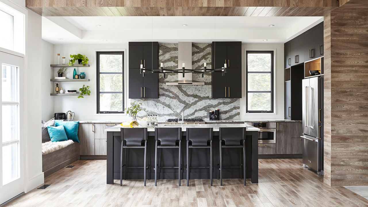 Kitchen with black cabinets, bodly veined quartz countertops and backsplash, wooden columns, ceilings, and floors, and plenty of natural light.