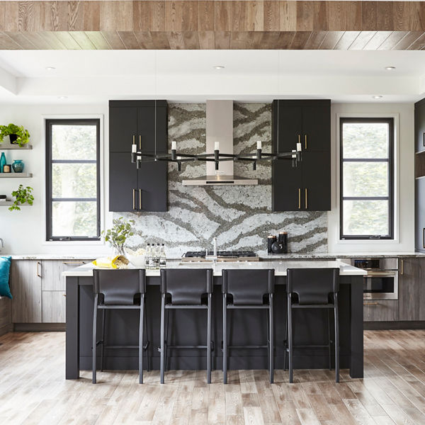 Kitchen with black cabinets, bodly veined quartz countertops and backsplash, wooden columns, ceilings, and floors, and plenty of natural light.
