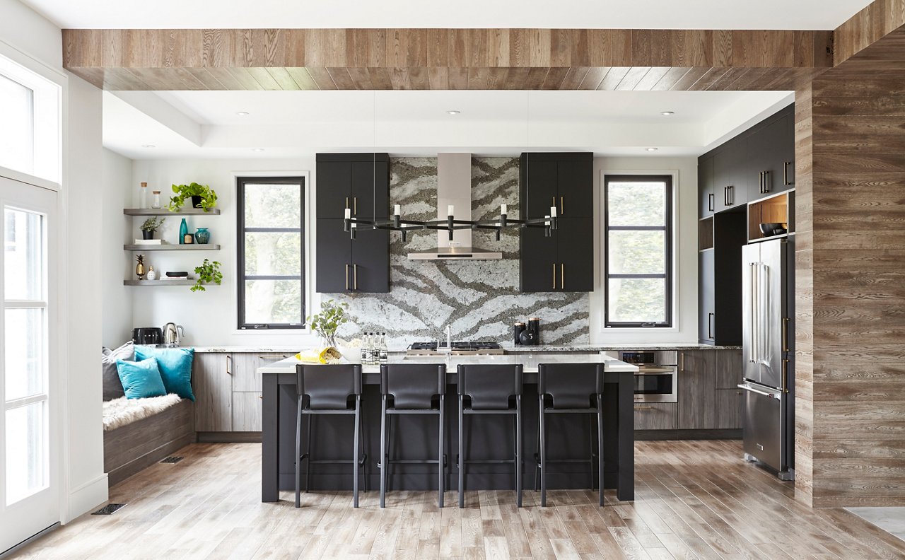 Kitchen with black cabinets, bodly veined quartz countertops and backsplash, wooden columns, ceilings, and floors, and plenty of natural light.