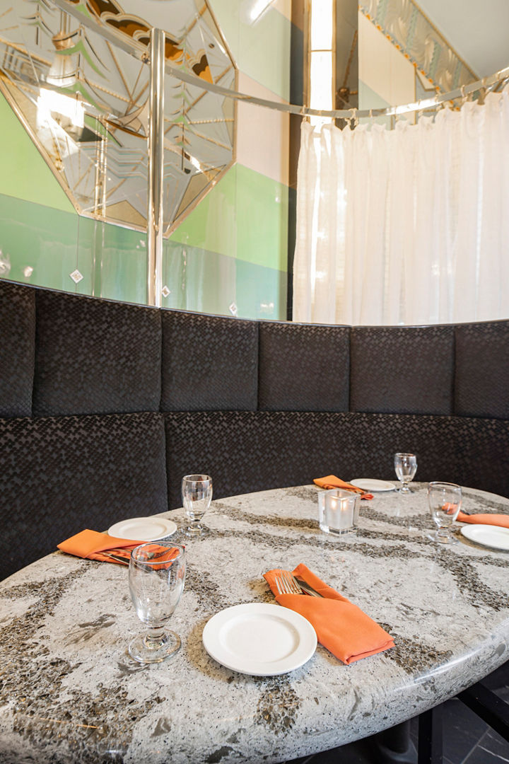 a restaurant booth with a table topped with white and gray veined quartz countertops and orange placeholders