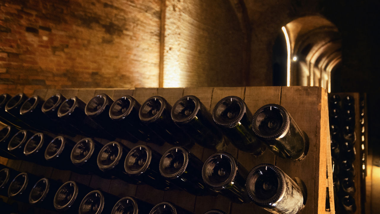 Pupitre and bottles inside an underground cellar for the production of traditional method sparkling wines in italy