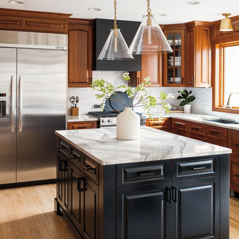 A kitchen with oak cabinets and an island with dark brown cabinets and a Harlow quartz countertop