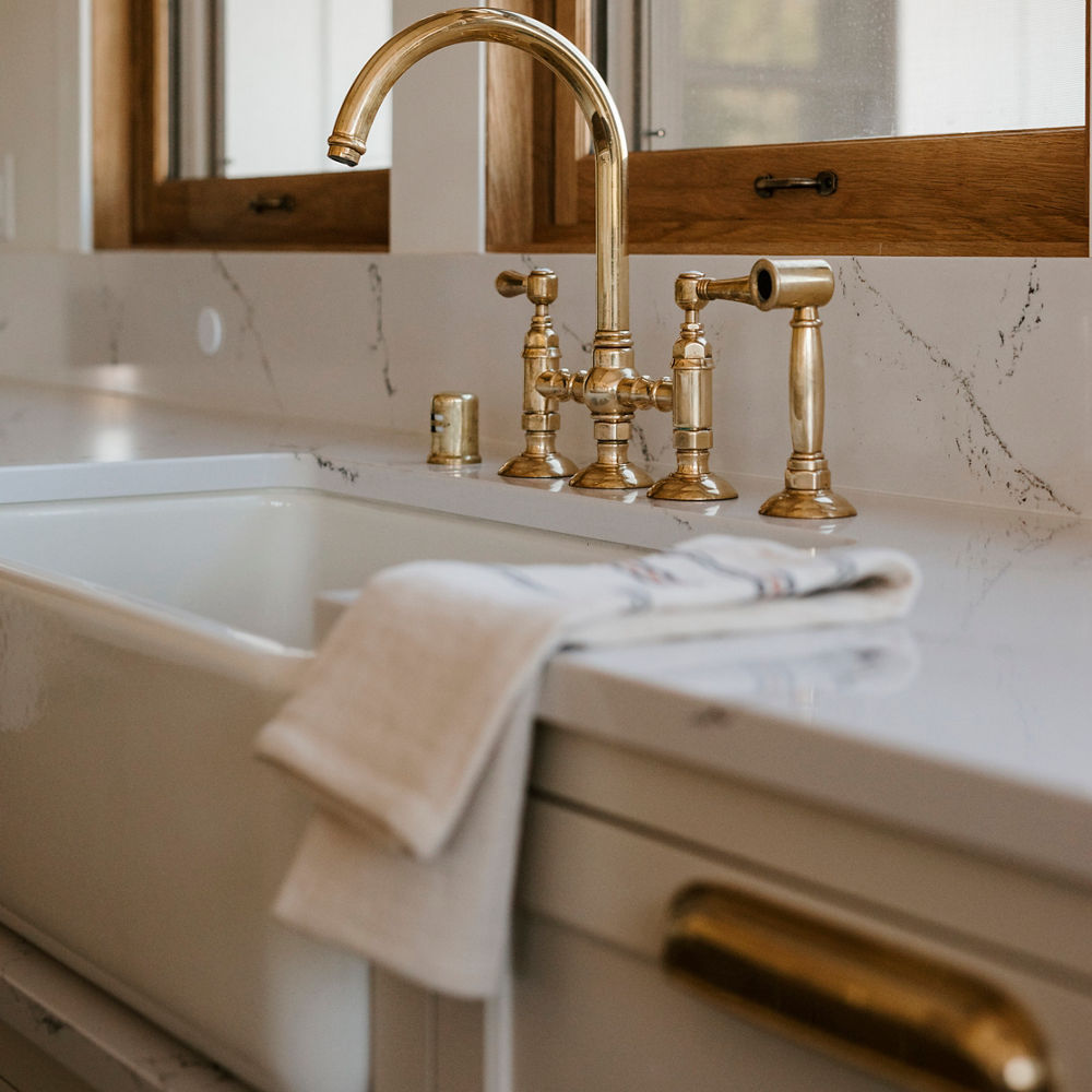 A faucet with a farmhouse sink and Hawksmoore quartz countertops