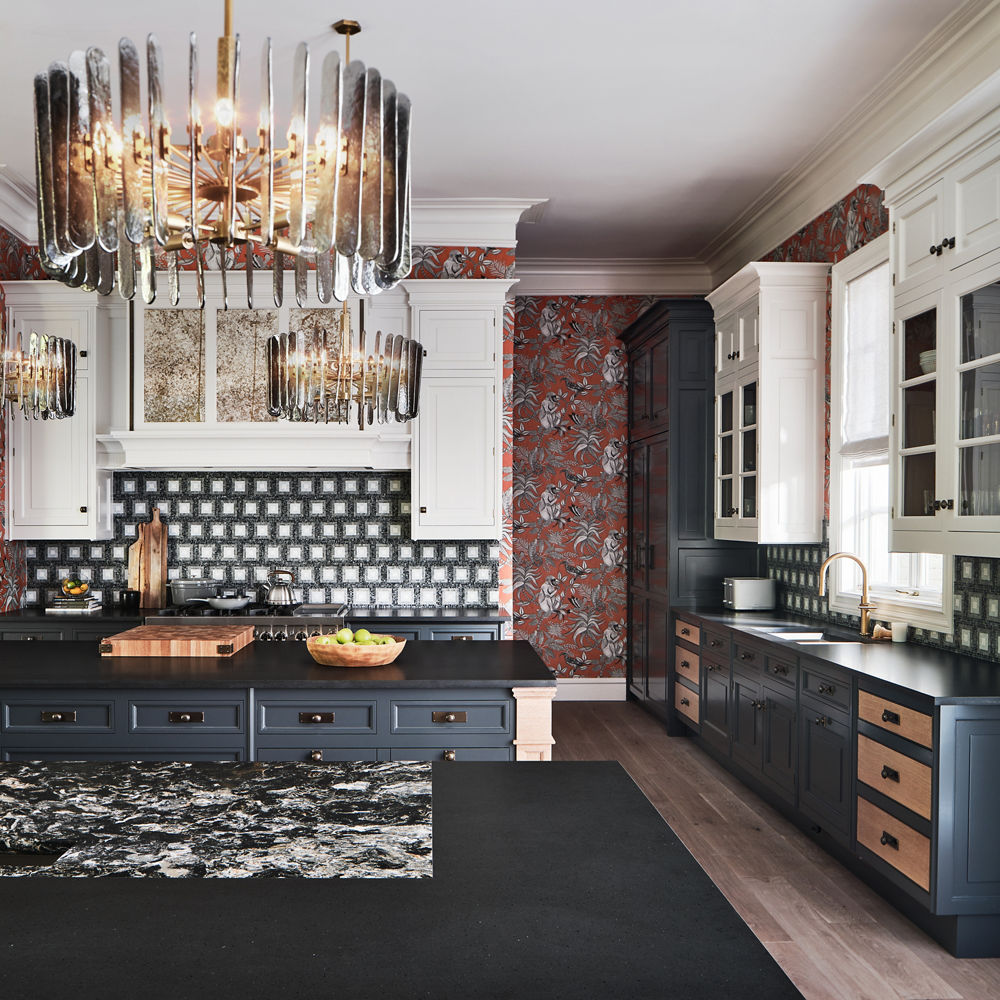 A kitchen with two toned black and white cabinets, tile backsplash, floral wallpaper and large light fixtures with Hollinsbrook Matte and Montana Midnight Matte quartz countertops