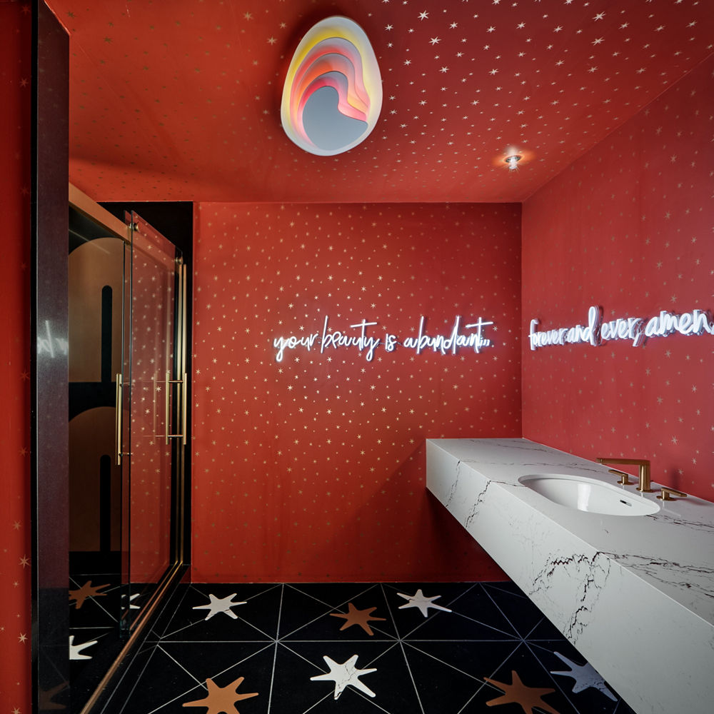 A dreamy bathroom space with red walls, stars on the wall, and an Inverness Bronze bathrom vanity