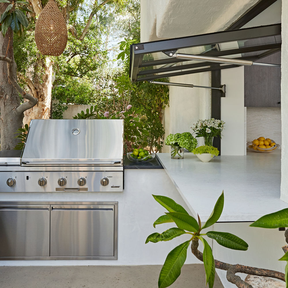 an outdoor patio with a grill and easy access to the kitchen through a giant window.