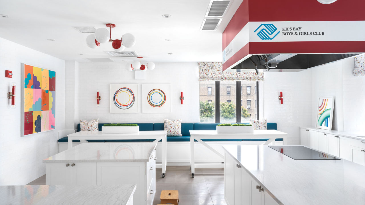 A kitchen in the Kips Bay Boys & Girls Club with white cabinets, white quartz countertops, and pops of color throughout.