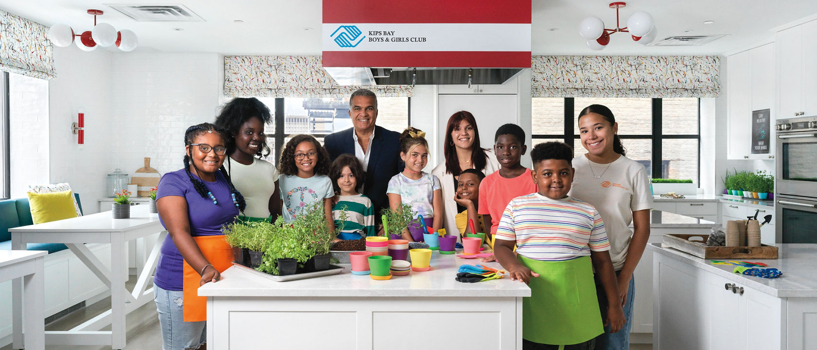 A kitchen in the Kips Bay Boys & Girls Club with white cabinets, white quartz countertops, and pops of color throughout.