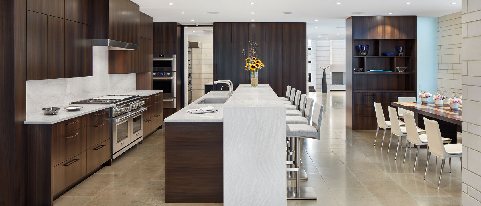 A modern kitchen with dark oak cabinets and an Ironsbridge quartz waterfall kitchen island.