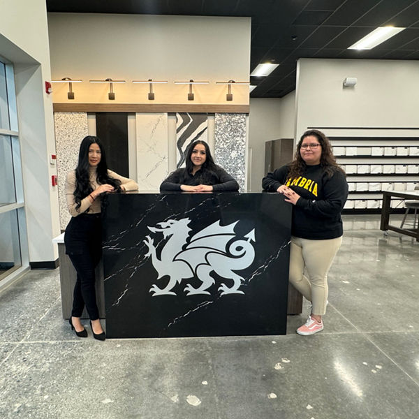 Three Cambria employees standing at table with the dragon logo