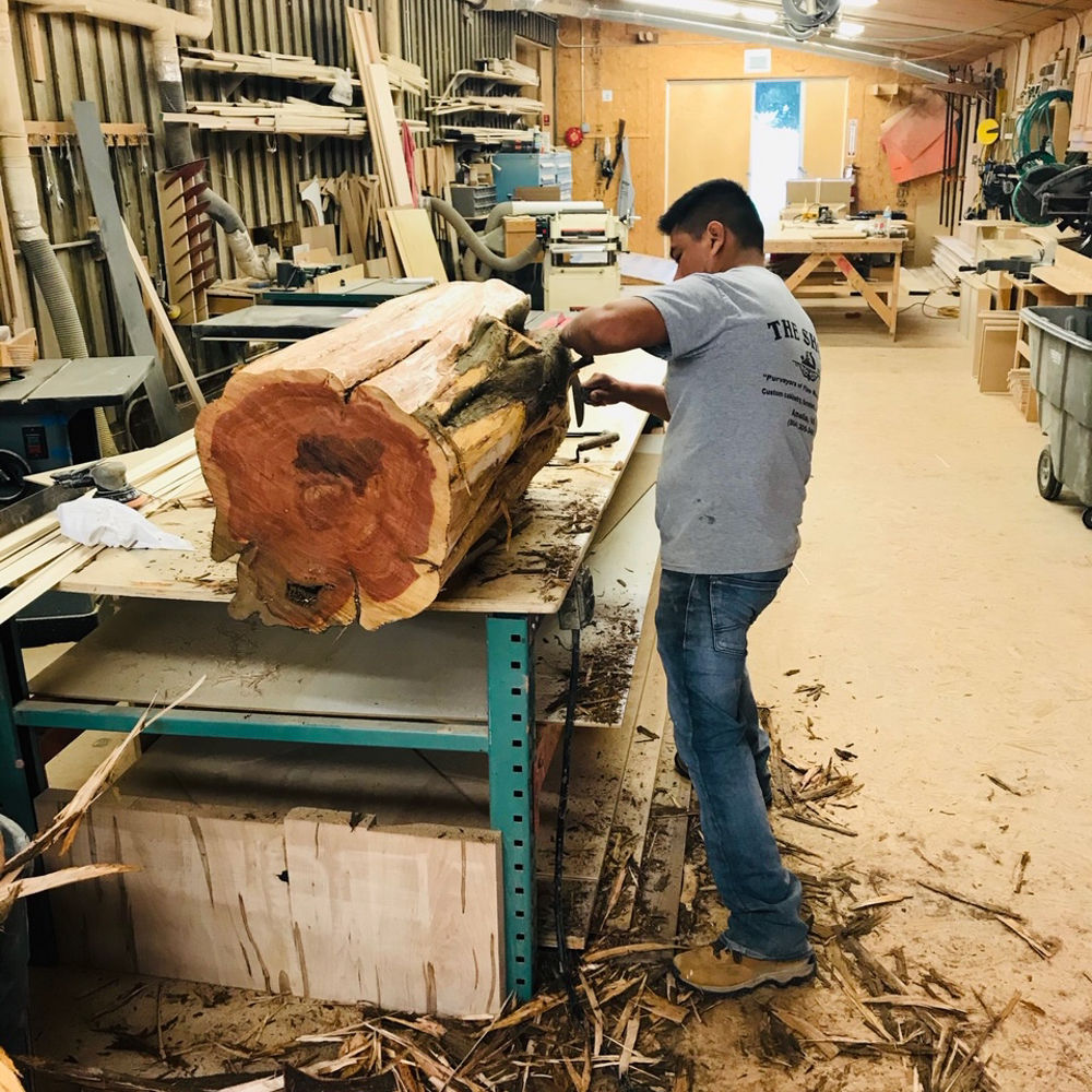 Professional working with a Cedar tree trunk to create dining table base