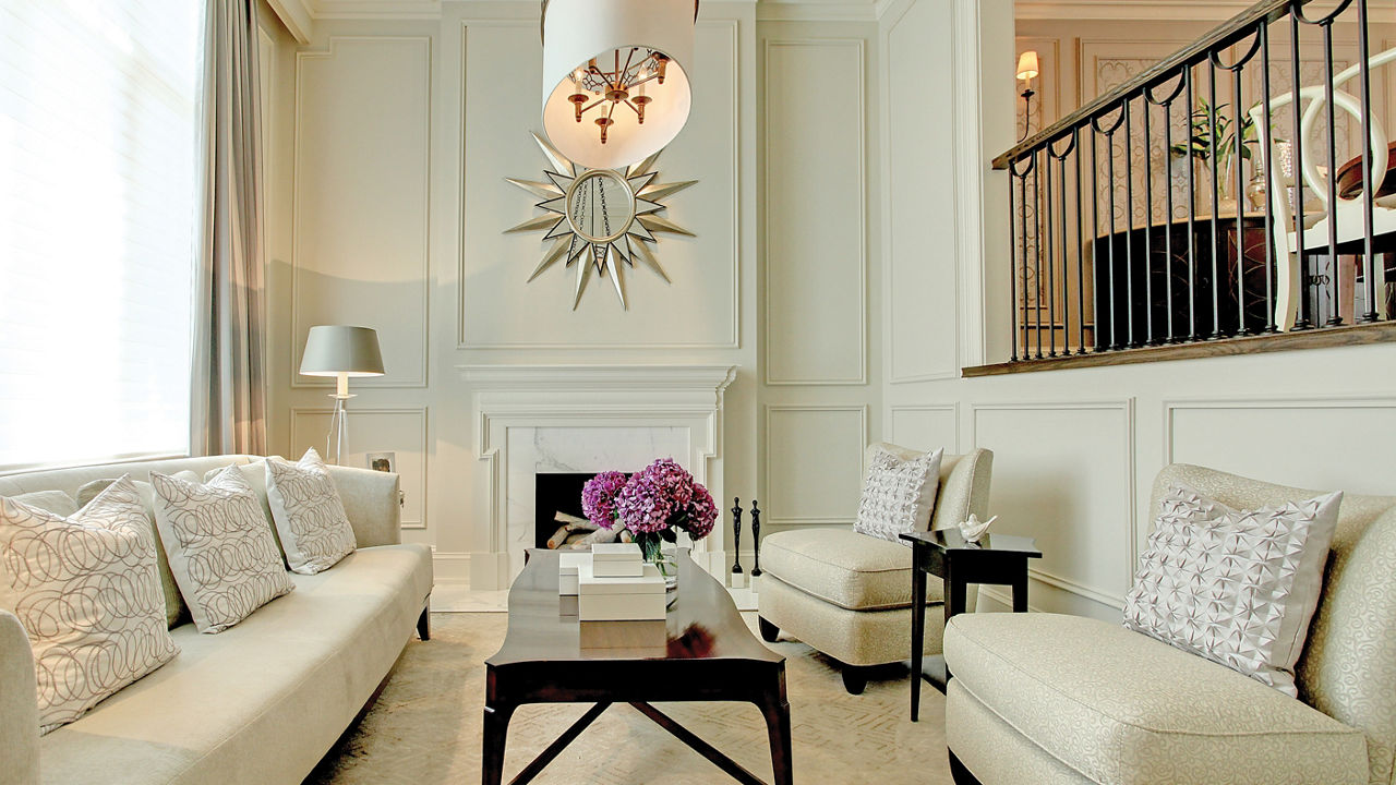 a gorgeous white living room with white furniture, white fireplace with sun shaped mirror, and wooden accent tables,