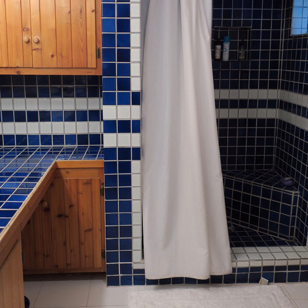 A bathroom with blue tile siding, countertop, and shower tiling.