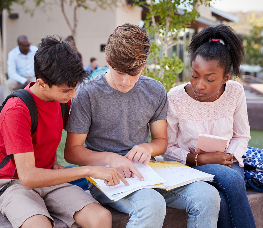 A group of kids reading papers in a folder.