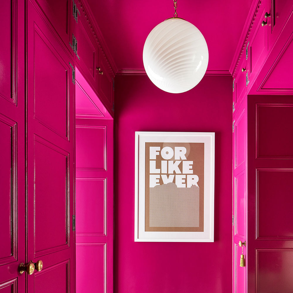 An entryway with hot pink walls, black and white quartz tiled flooring, and a gorgeous light fixture.