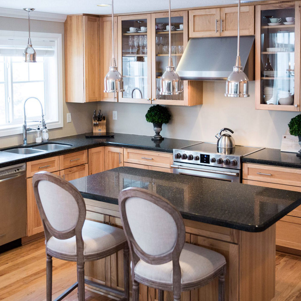 A before image featuring a kitchen with counters and an island with dark granite.