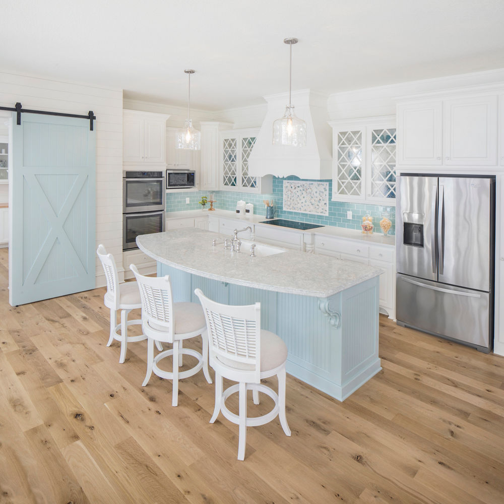 White kitchen with pale blue island featuring Cambria Montgomery.