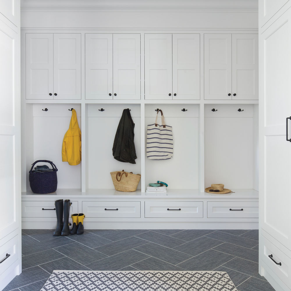 A coastal inspired mudroom with white cubbies, gray tiled flooring, and plenty of storage space.
