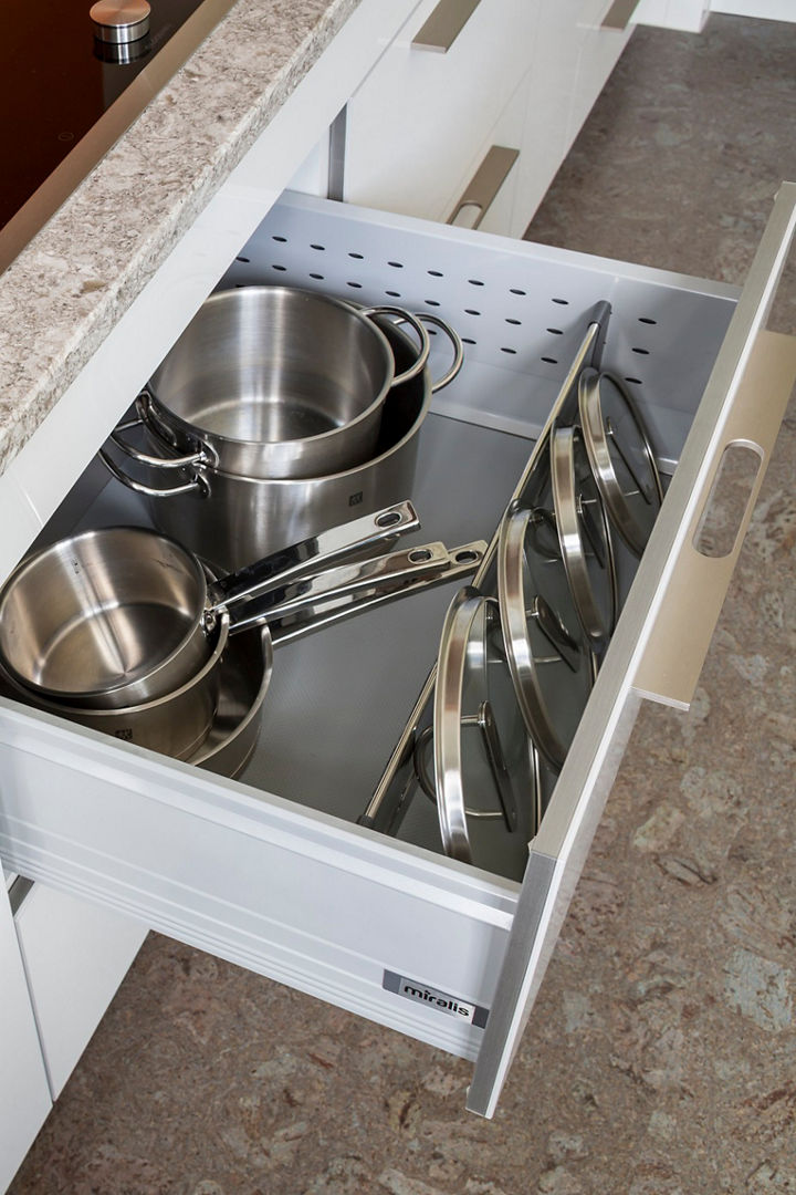 A kitchen drawer with various pots and cup measurers.
