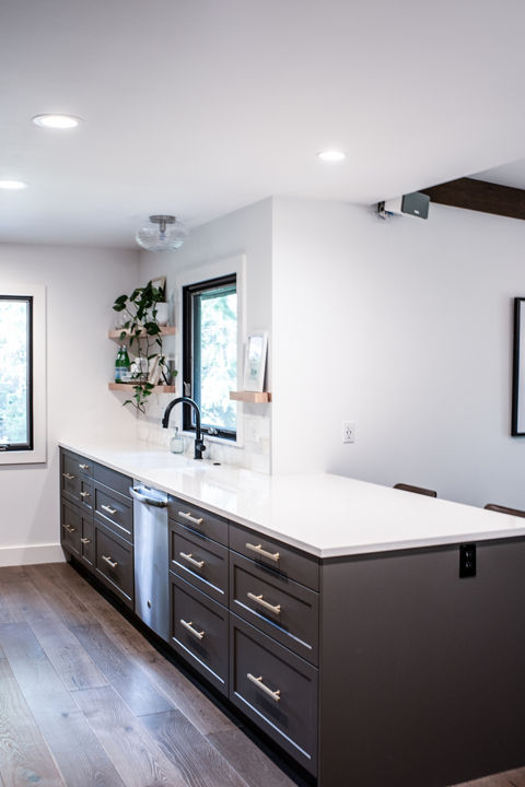 a simple kitchen with dark brown cabinets, white quartz countertops, and plenty of natural lighting.