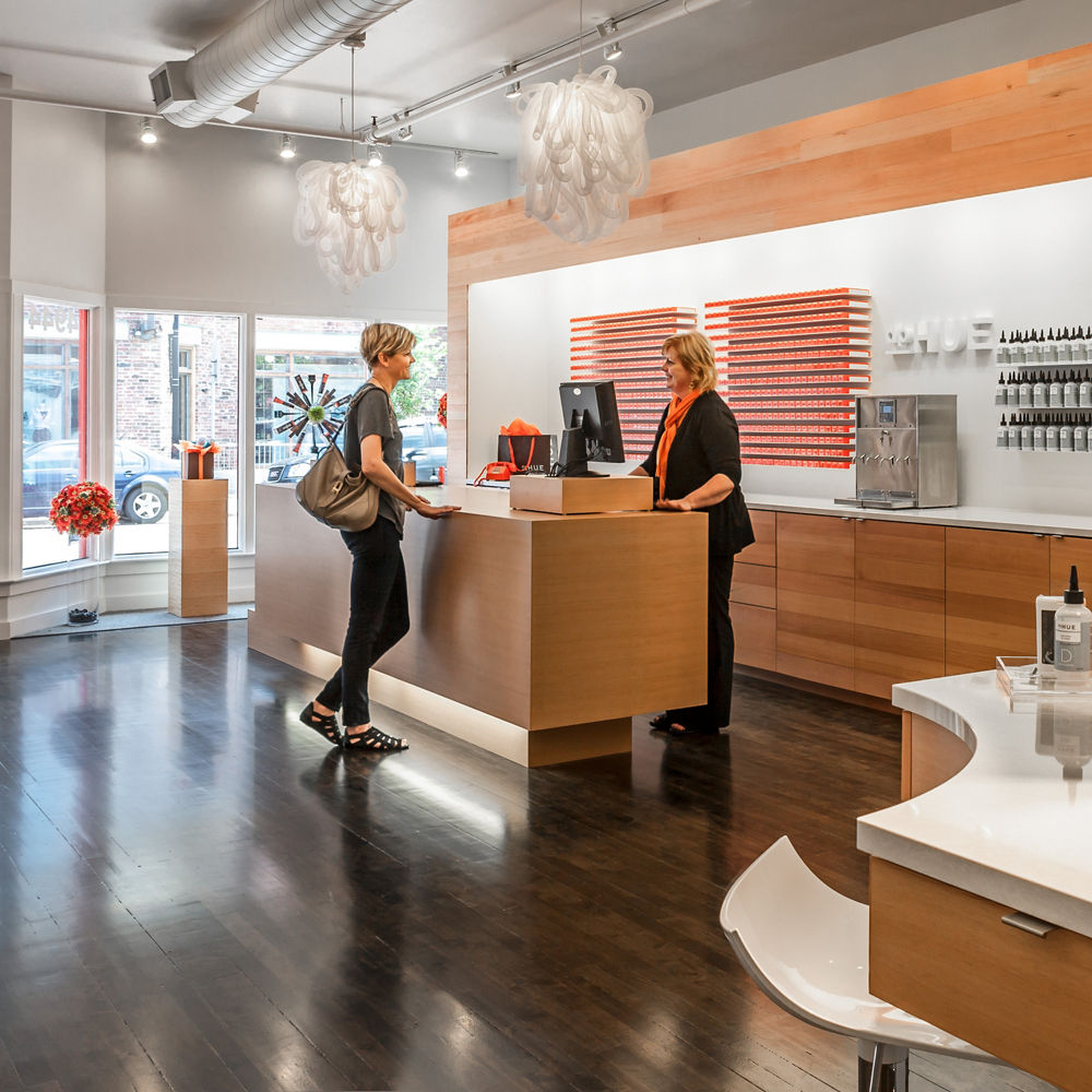 A woman greeting a client at the dpHUE salon, featuring Newport quartz countertops