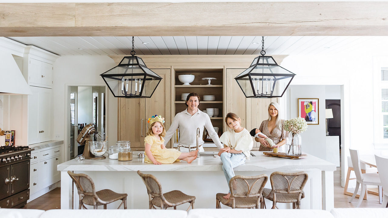 T.J Oshie and his family posing in their renovated kitchen featuring Cambria Brittanicca Warm Matte™ quartz countertops.