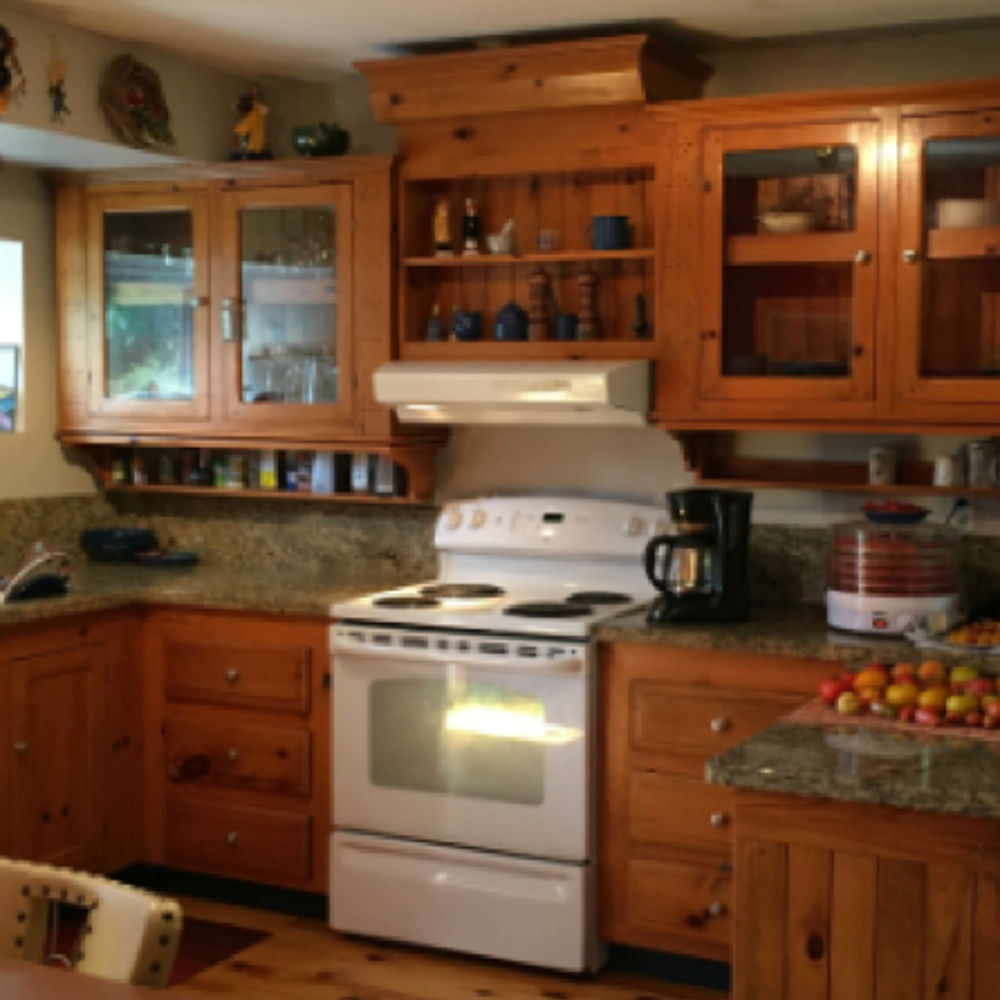 Before image of kitchen with wooden cabinetry and dark countertops.