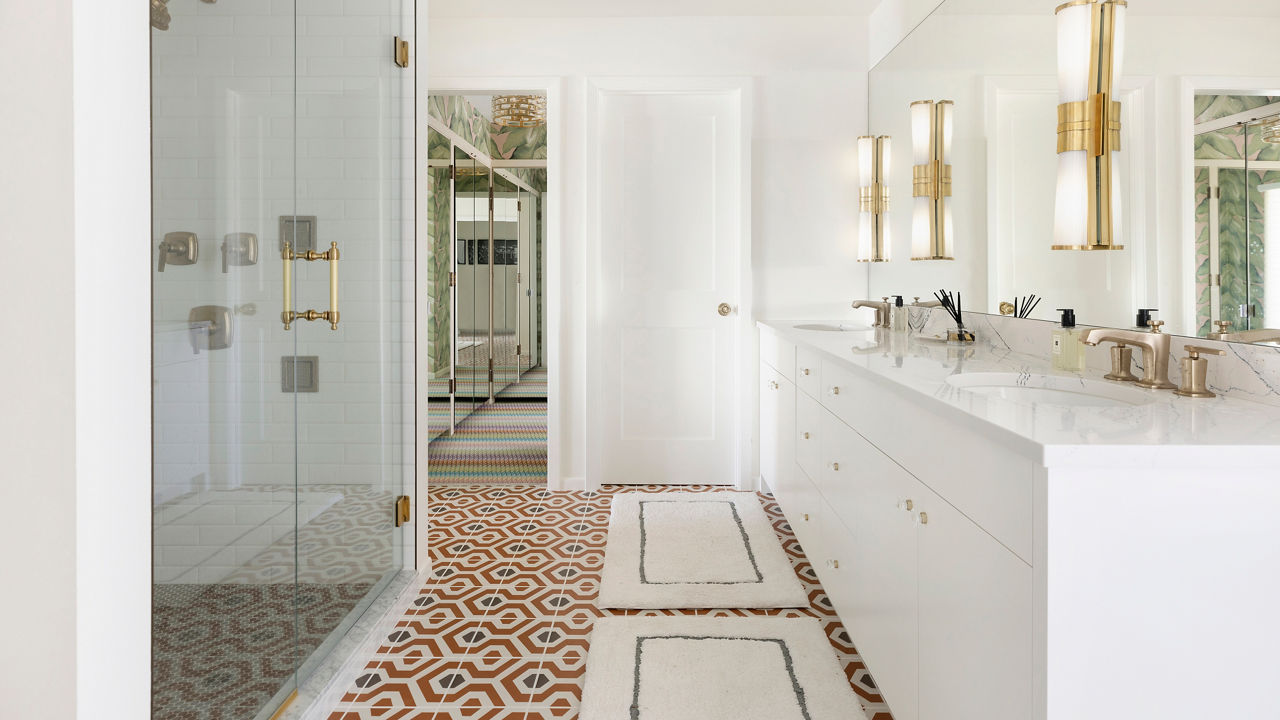 a luxurious bathroom with a white vanity topped with white and blue veined quartz countertops, a large walk-in shower, and gold accents throughout.