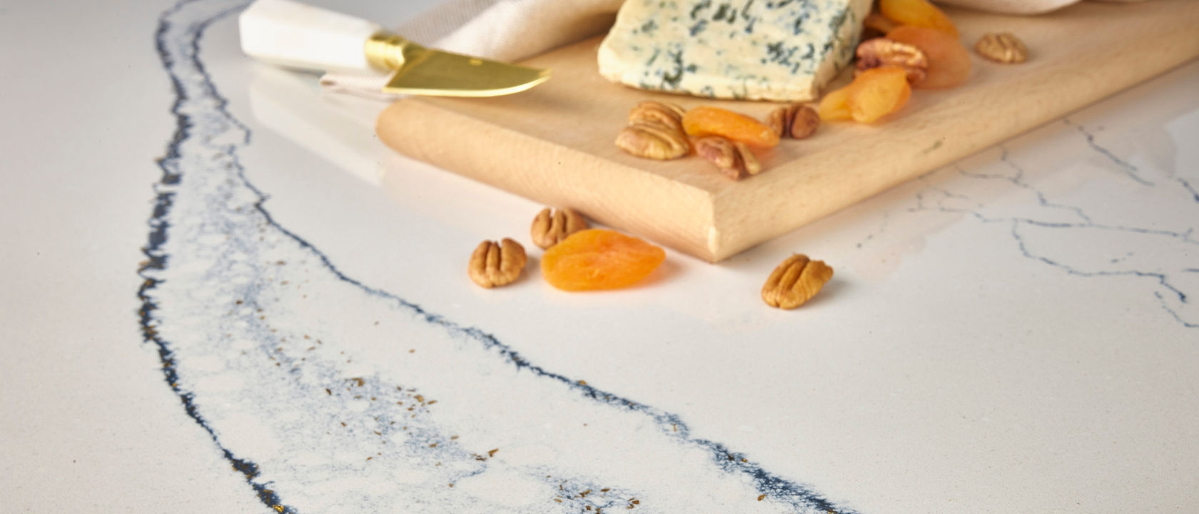 Portrush features a warm white base crisscrossed with bold navy, gray, and black veins accompanied by fine-spun filaments and gleaming gold flakes.