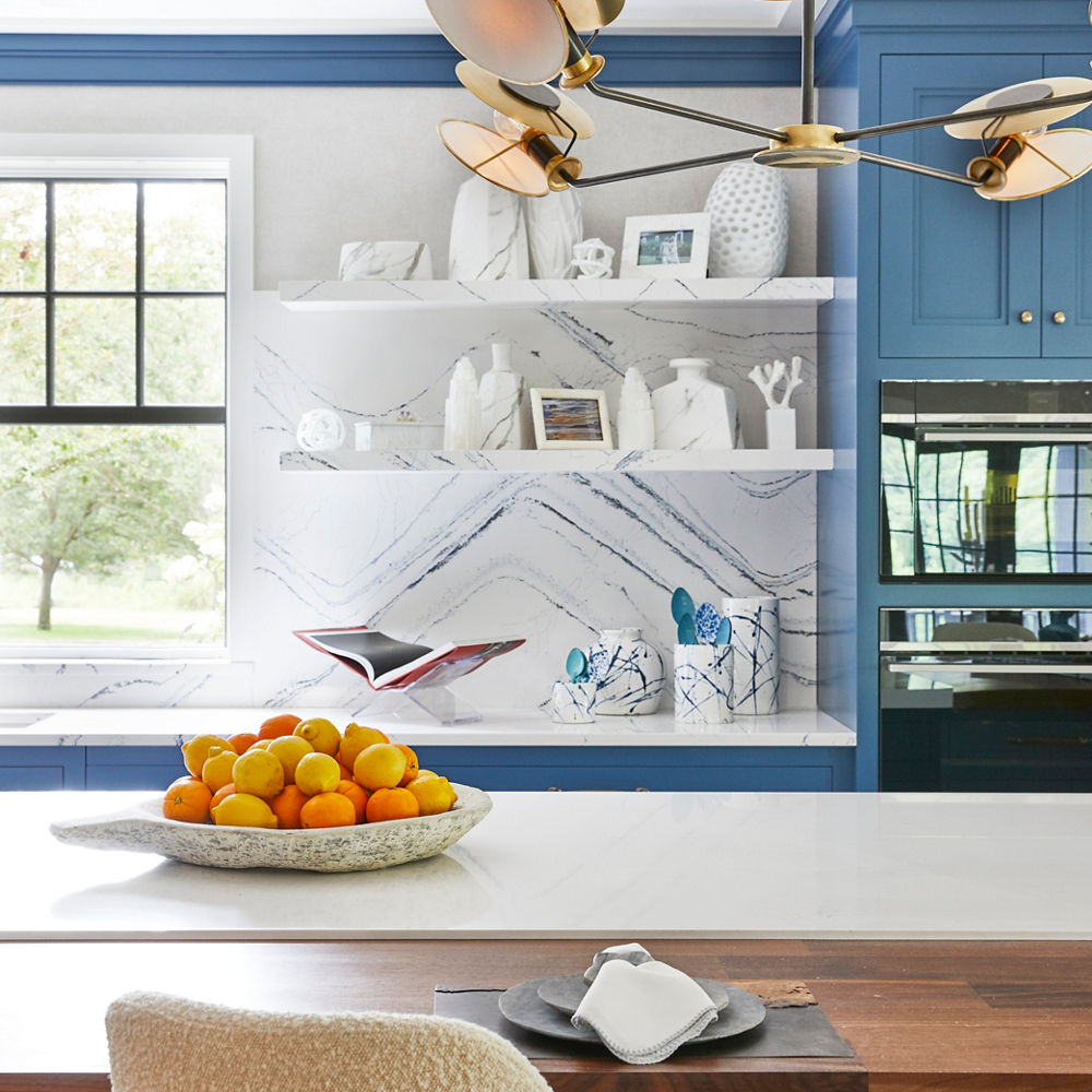 open shelving made from white quartz matches with the countertops and backsplash in the this blue and white kitchen.