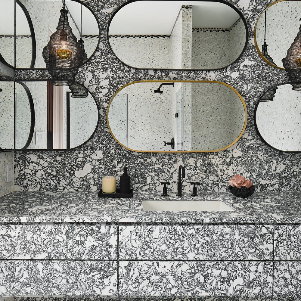 A bold bathroom with Rose Bay Matte Quartz countertops and matching backsplash, with multiple oval shaped mirrors in various neutral colors.