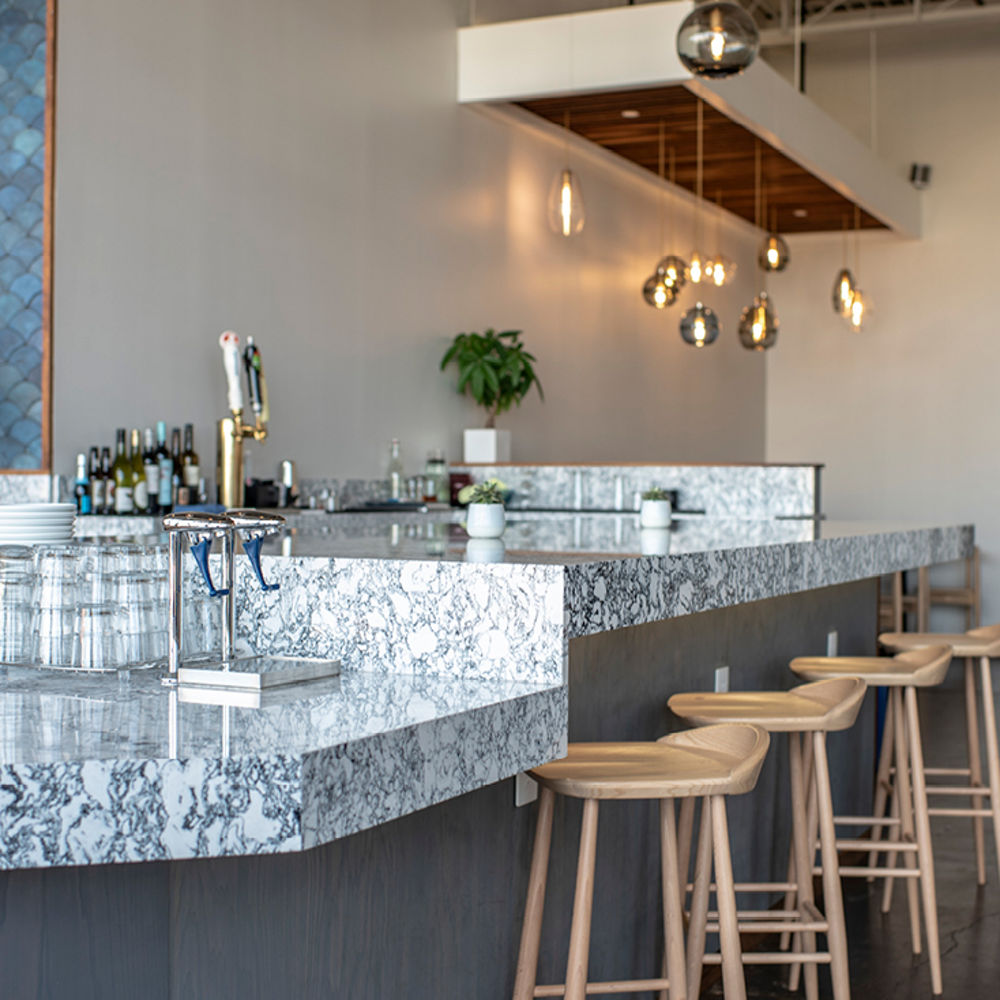 a cafe with barstool seating at a bar topped with black and white quartz countertops.