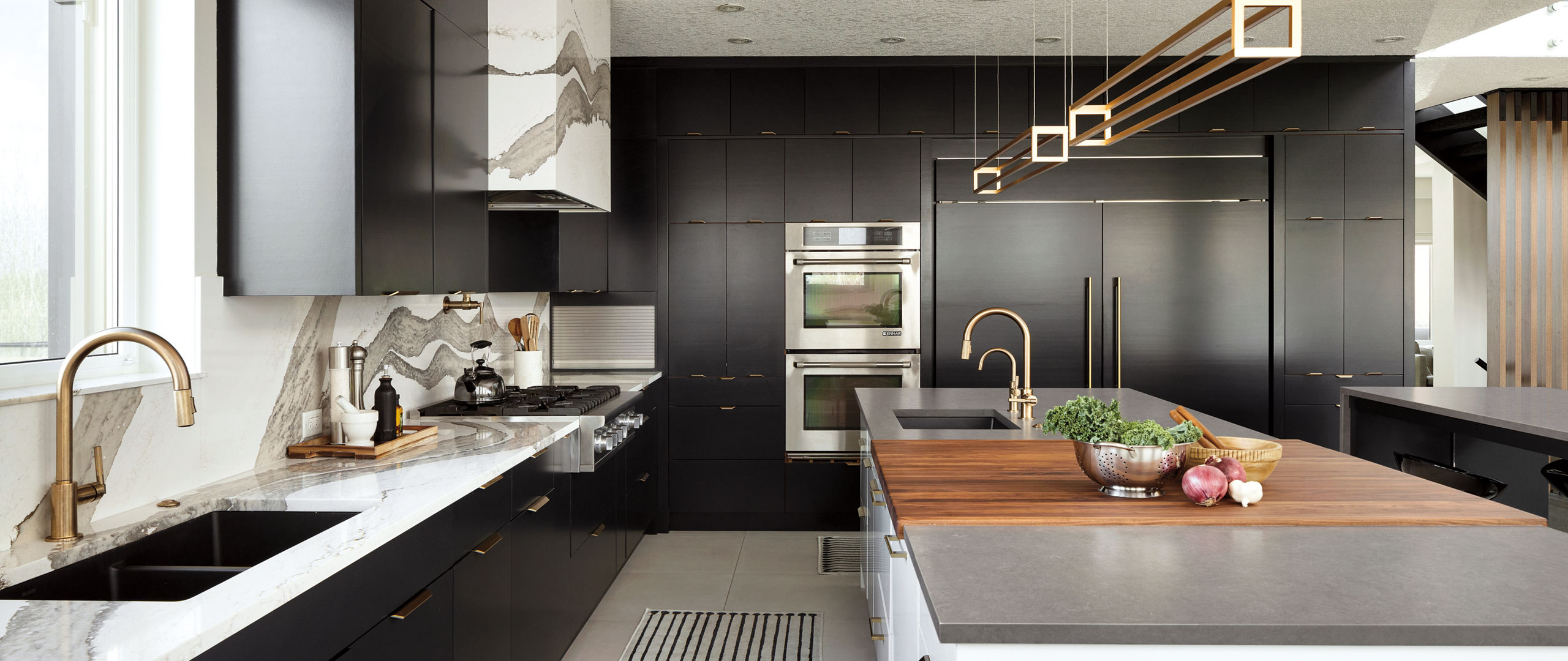 Kitchen with Skara brae and Carrick quartz countertops, dark wood cabinets and brass hardware