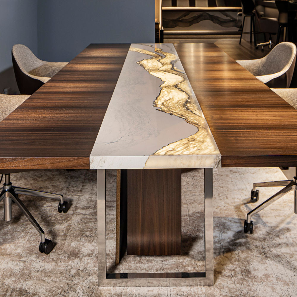 A conference table made from wood with a white quartz slab down the center with a backlit feature.